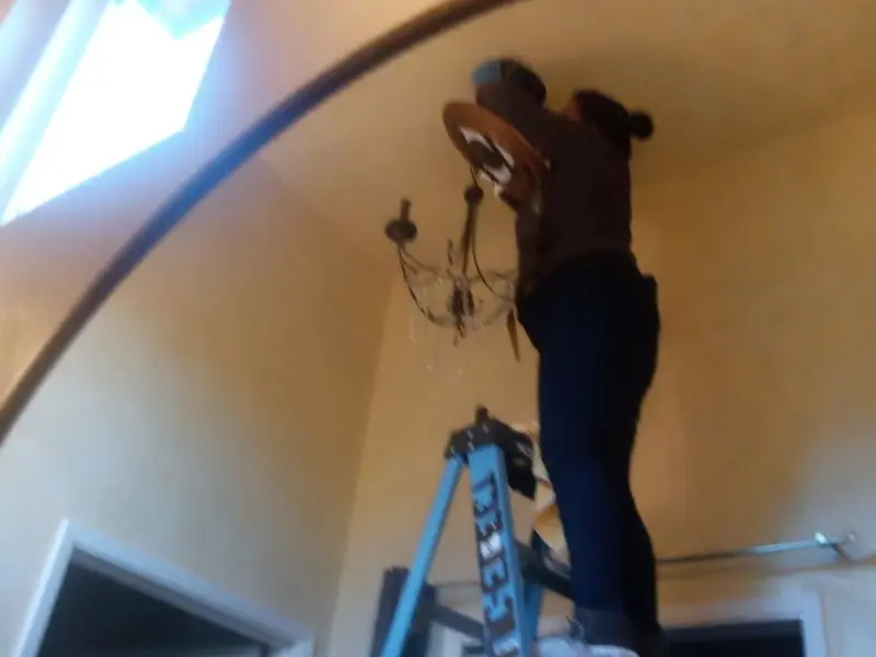Electrician installing a chandelier in a Sloan residence